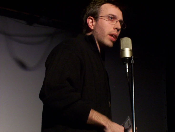 a man wearing glasses speaking into a microphone