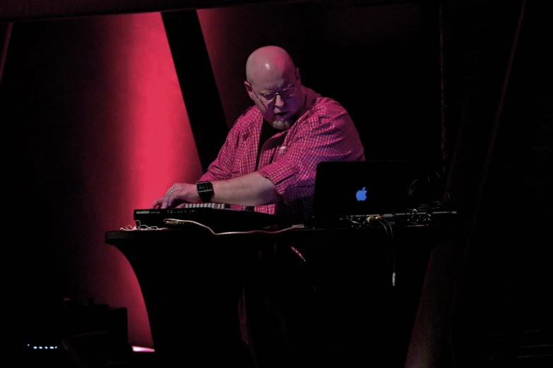 man playing laptop on stage at night with red light