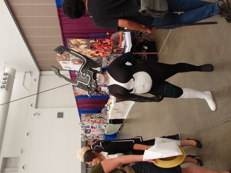 a person dressed in a bodysuit stands near many people