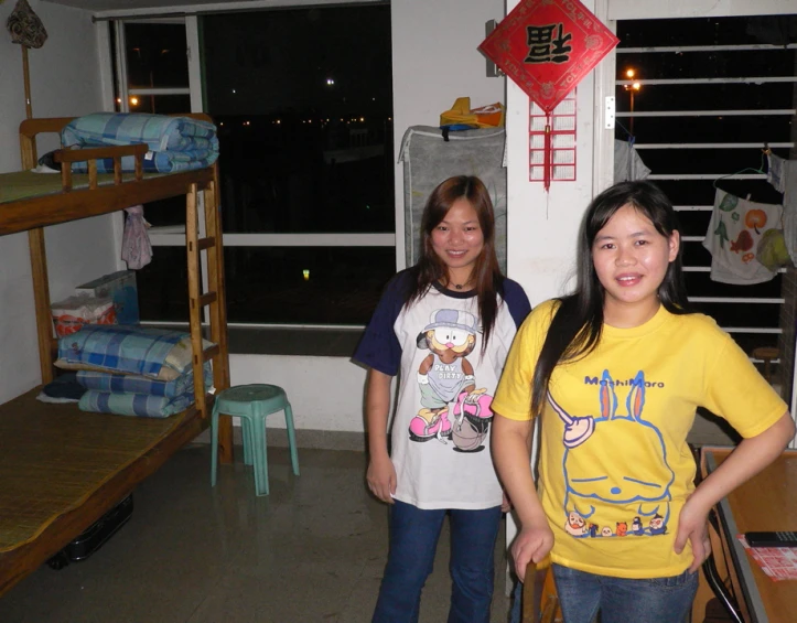 two young women are standing by their bunk beds