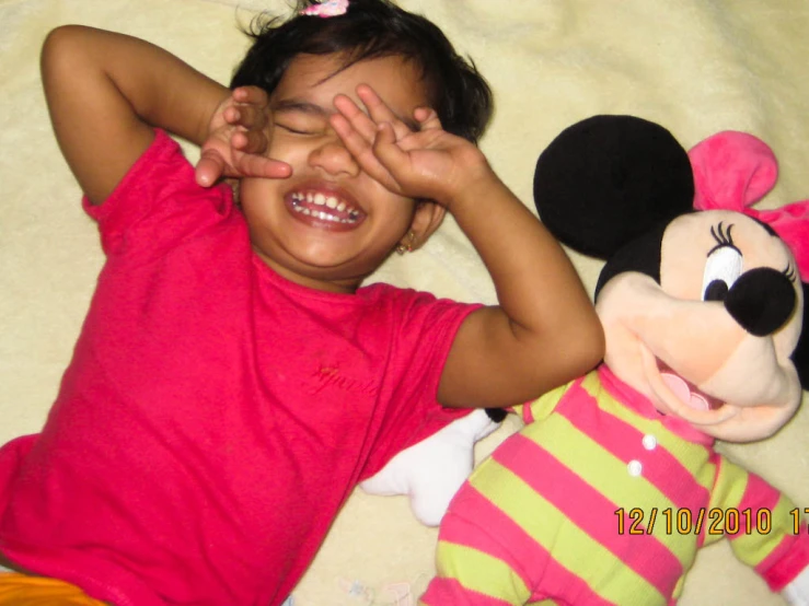 little girl on bed with stuffed mickey mouse