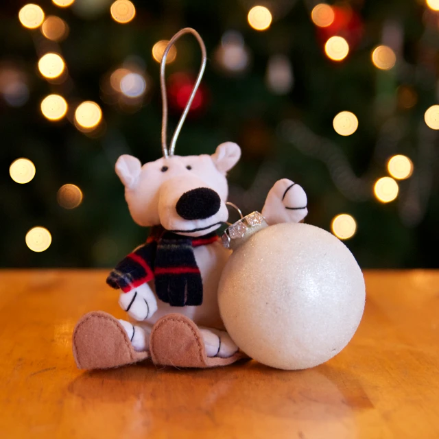 a bear holding on to an ornament for christmas