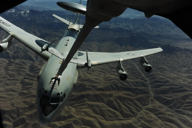 a propeller plane is flying over a mountainous area