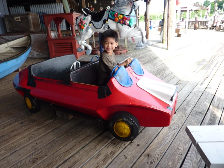 a boy on a toy car with a horse in the background