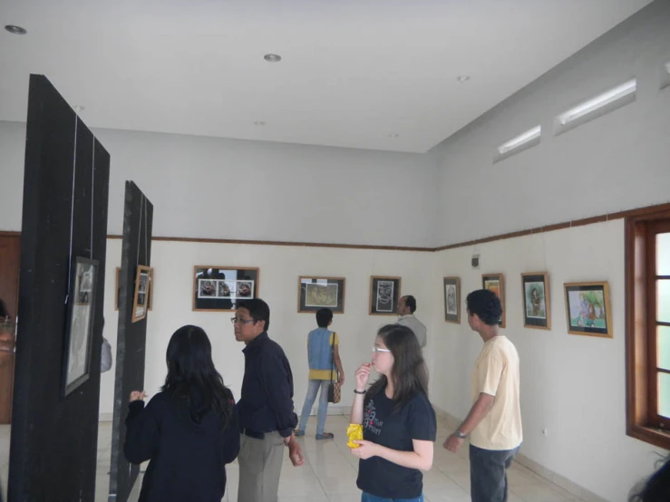 four adults standing in room looking at pictures