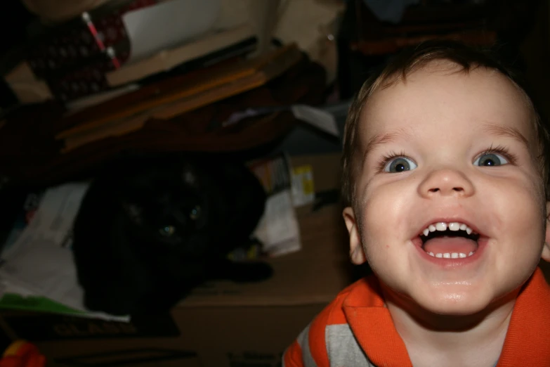 a small child laughs in front of a black cat