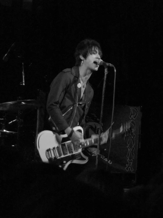 a young man is playing a guitar while the audience looks on