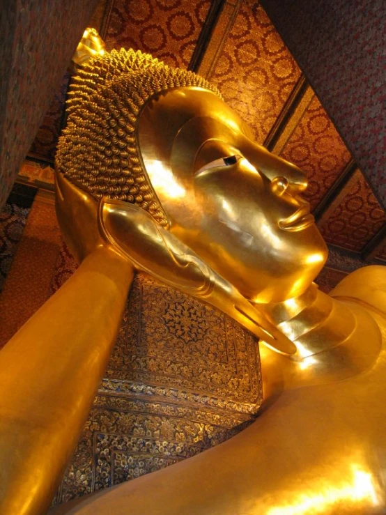 an ancient gold statue sits atop a shiny, gold plated pedestal