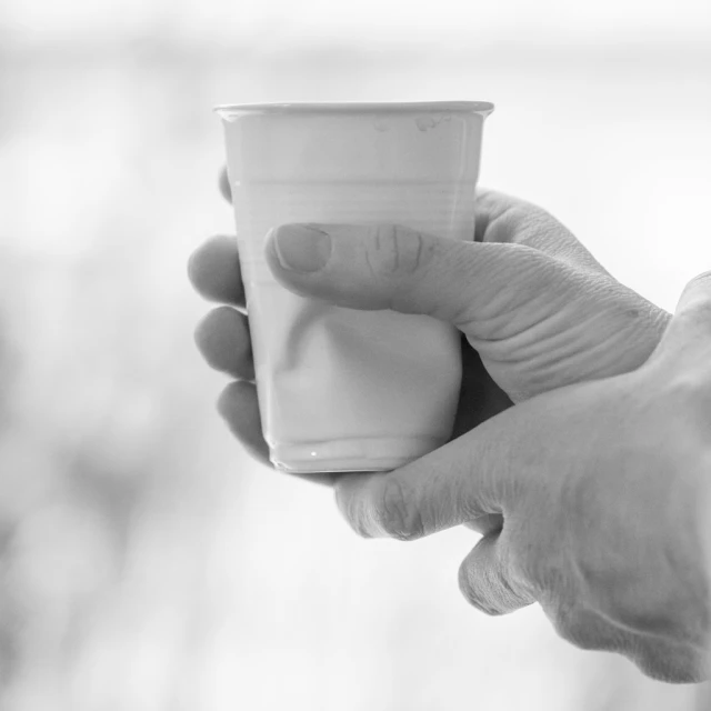 black and white image of a man holding a paper cup