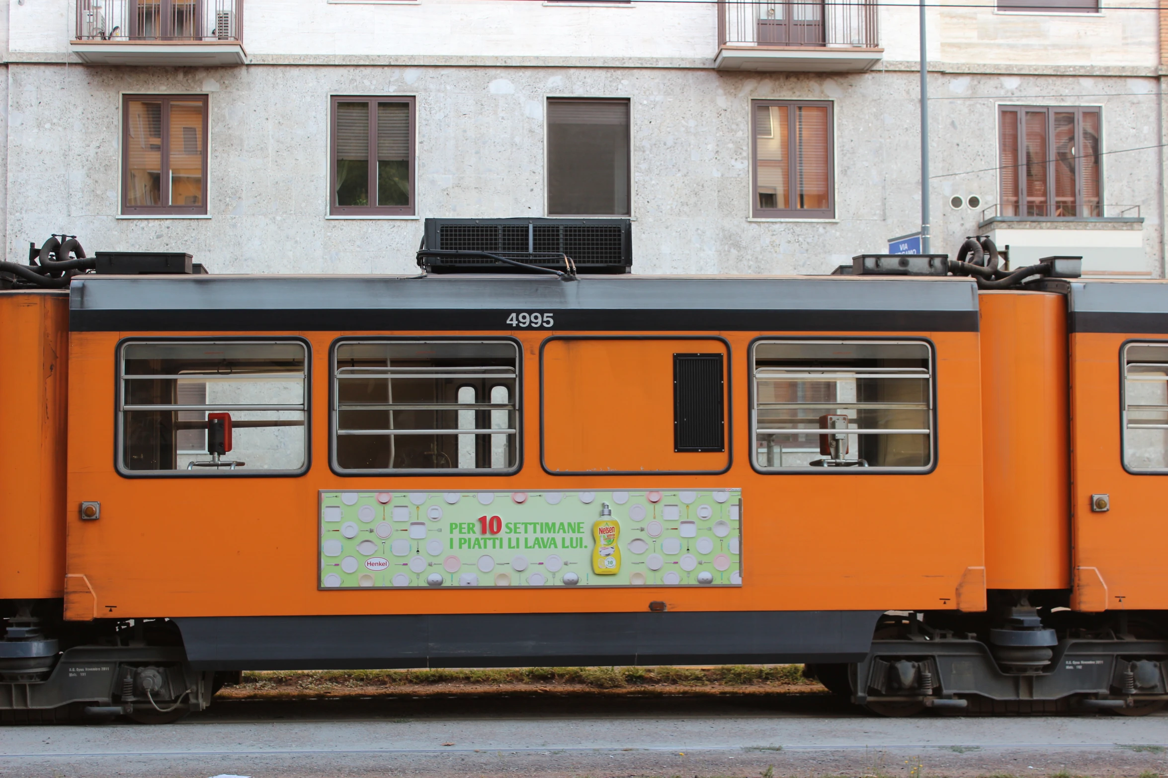 an orange electric trolley sitting outside next to a building