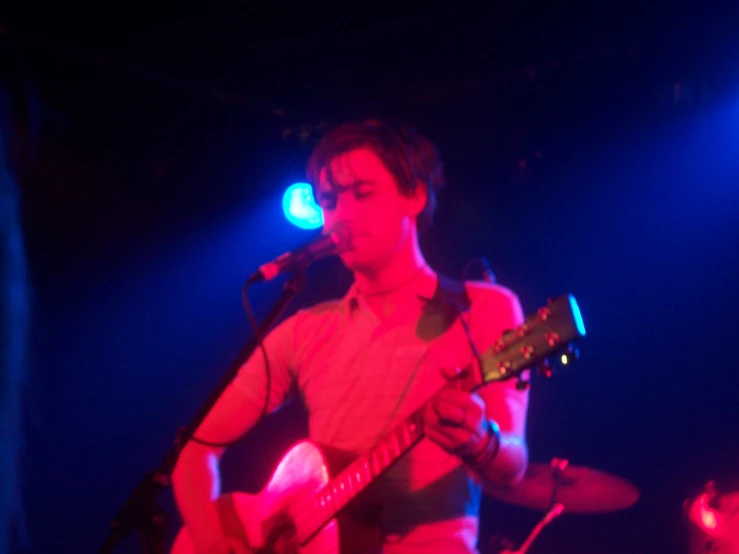 man with acoustic instrument in front of microphone on stage