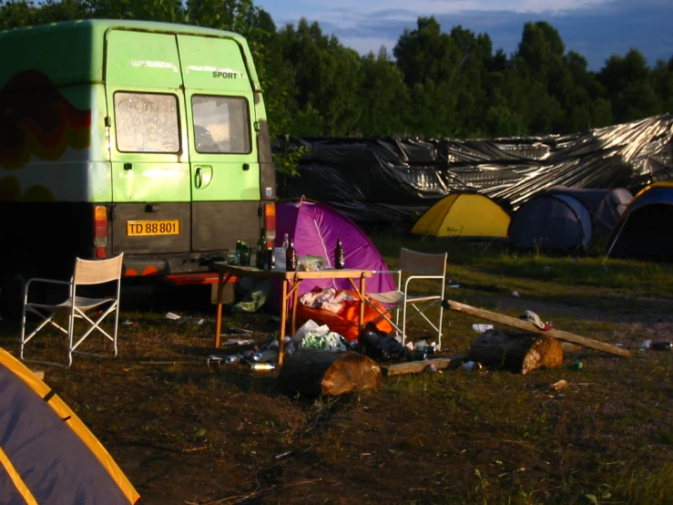 a view of an outdoor camping site with furniture and a parked vehicle