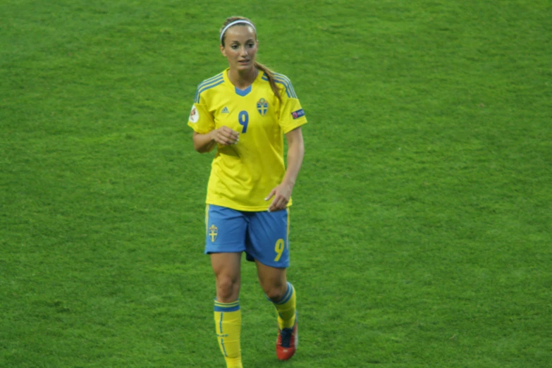 a female soccer player in a uniform is running on the field