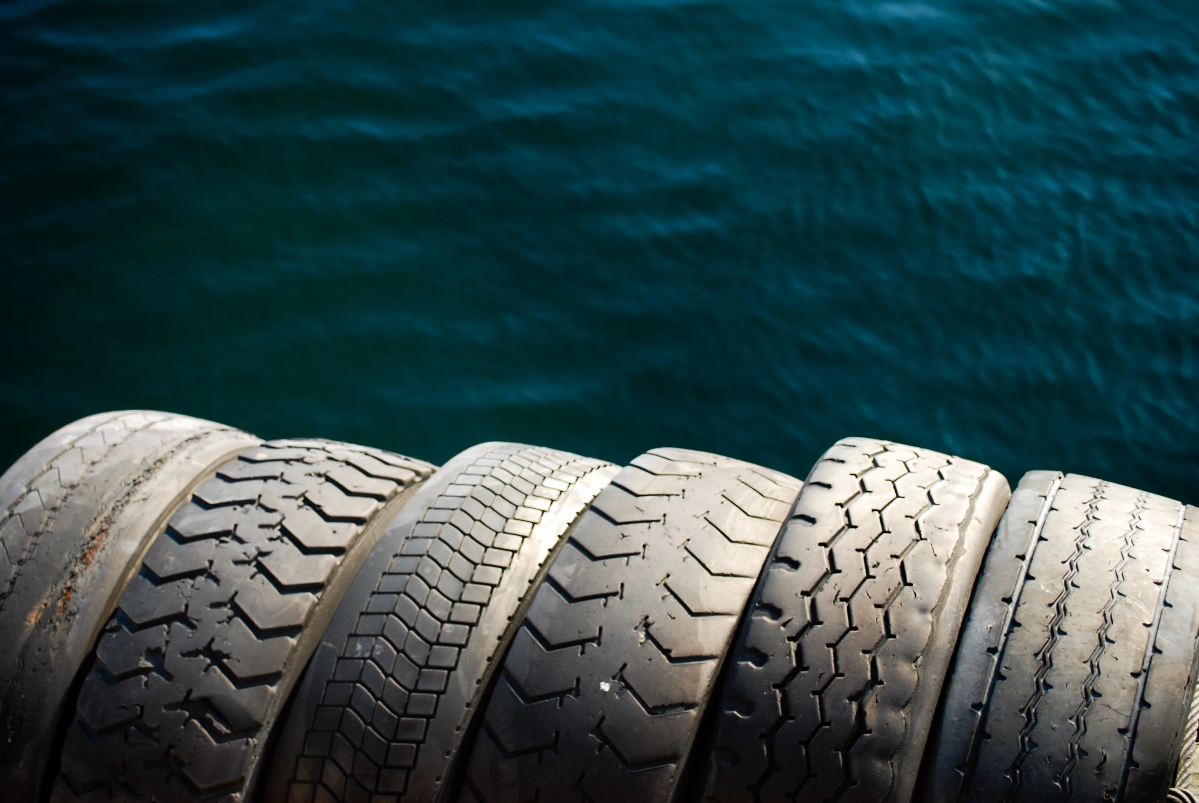 many small tires stand in the foreground next to a body of water