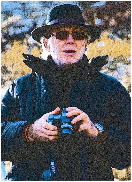 a man in a black hat is holding a camera