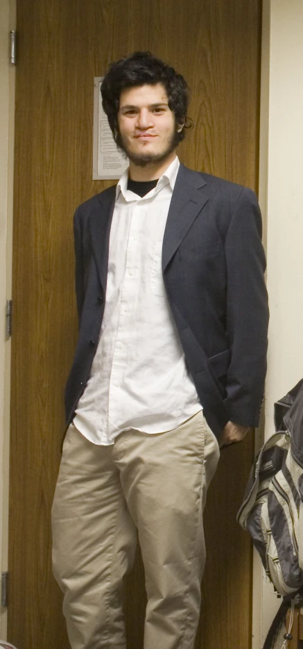 a young man is standing in a doorway wearing beige pants
