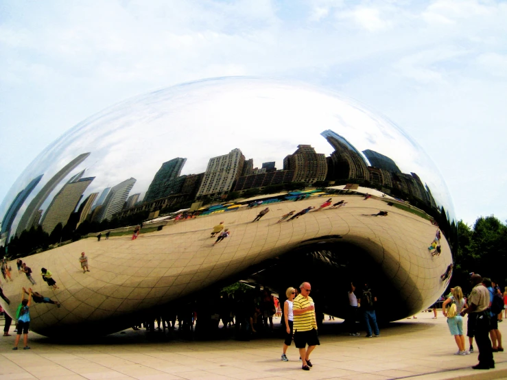several people standing outside of a giant, shiny object