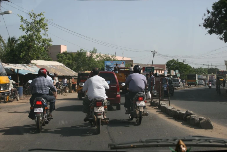 several people on motor bikes are riding down the street