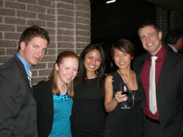 four people are posing for a picture while wearing suits