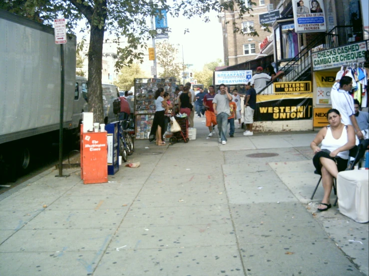 a crowd of people standing around on the sidewalk