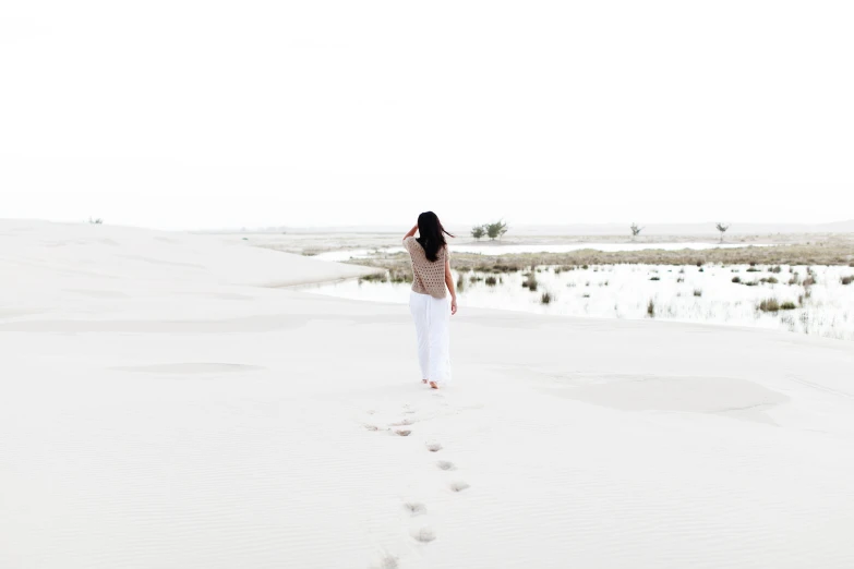 there is a woman walking through the sand