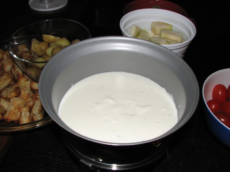 a bowl full of cream next to bowls with cherries