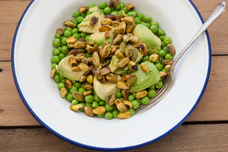 a large bowl full of peas, avocado and nuts