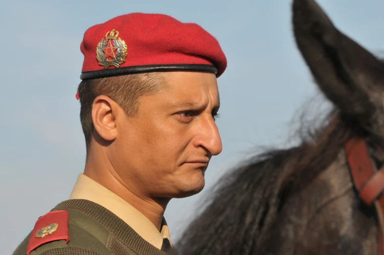 a military man in uniform is standing by a horse