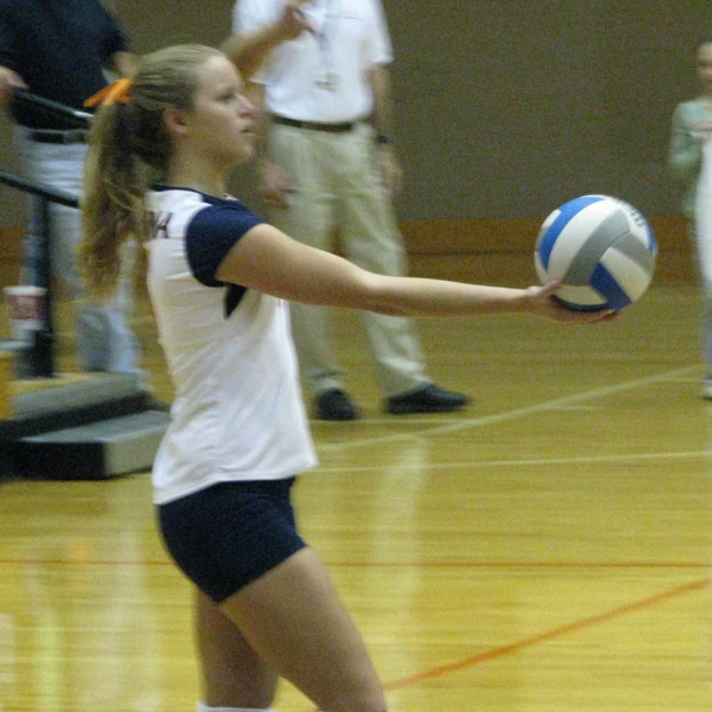 a girl about to serve a volleyball on a court