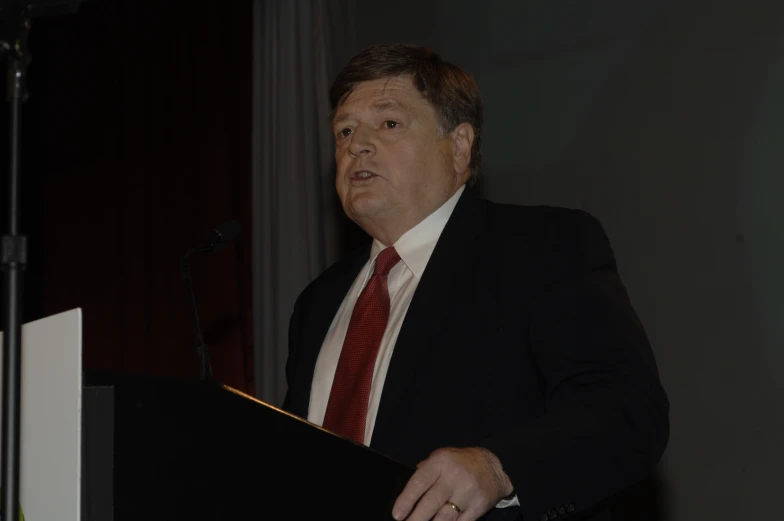 a man speaking at an event in front of a crowd