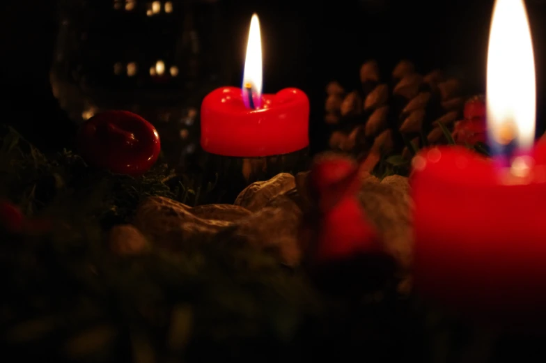 three candles sit beside two cones of red