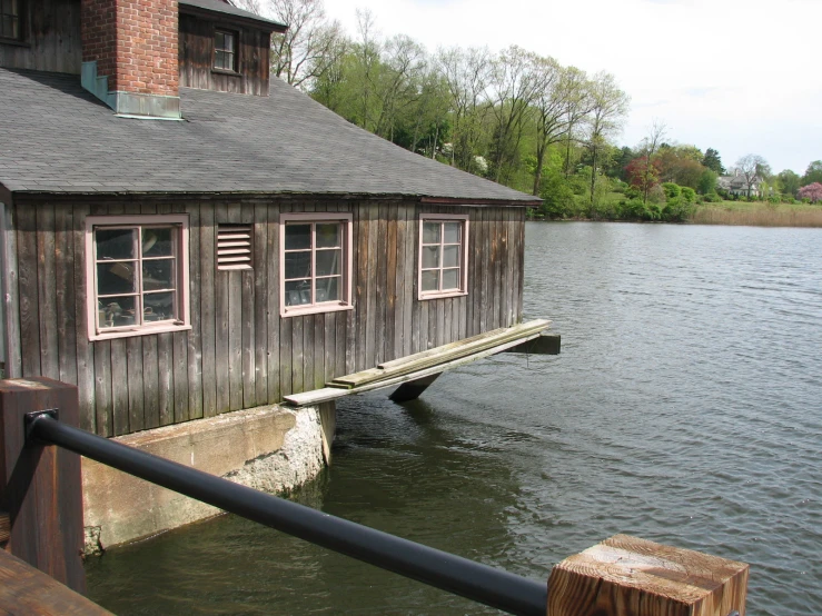 a building sitting on top of a body of water next to a wooden pier