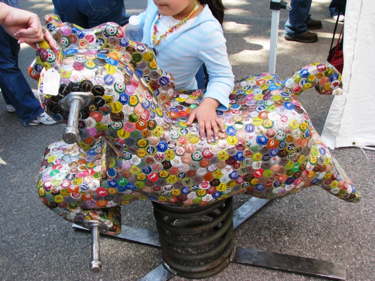 a girl holds onto the statue of a large elephant