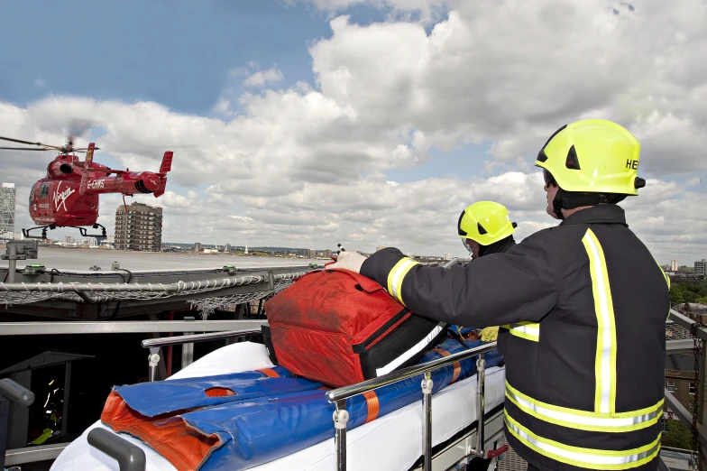 two people in life jackets on a boat looking at a red helicopter