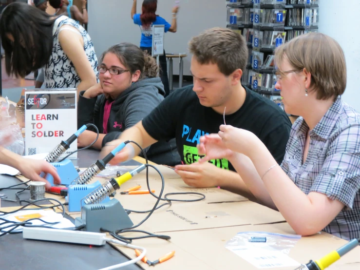 people sitting at a table looking at wires attached to a device