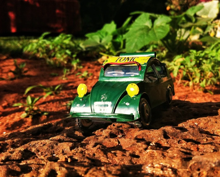 a toy car sitting on top of a sandy ground