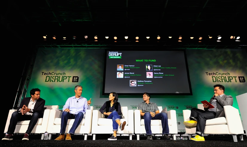 five men sit in white chairs at the panel