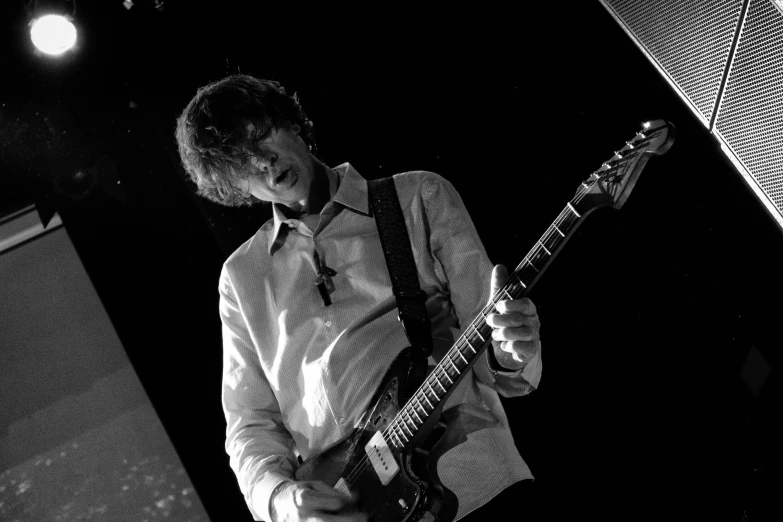 a man with a tie playing guitar in black and white