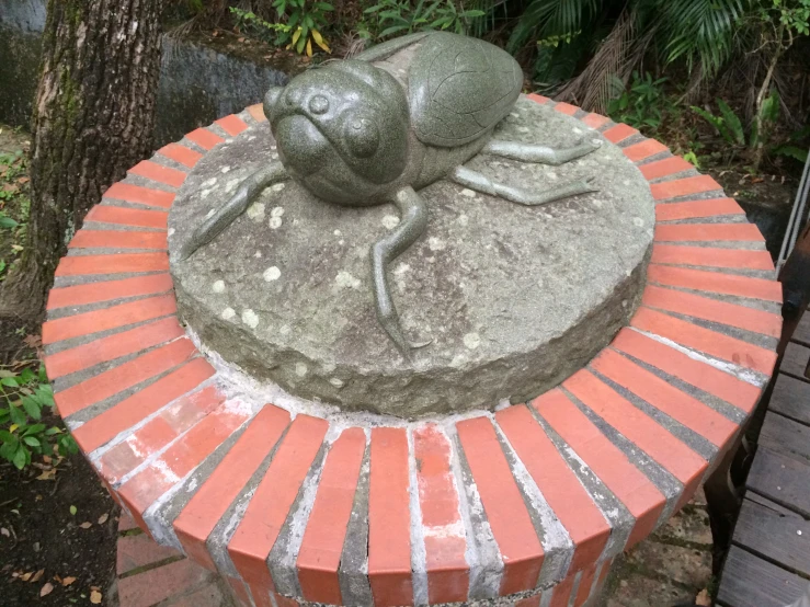 a frog statue sitting on top of a stone