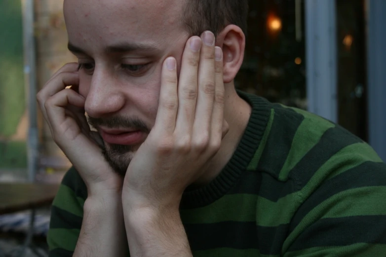 a man is holding his hands together and talking on a cell phone