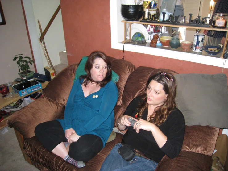 two women sit on the couch and play video games