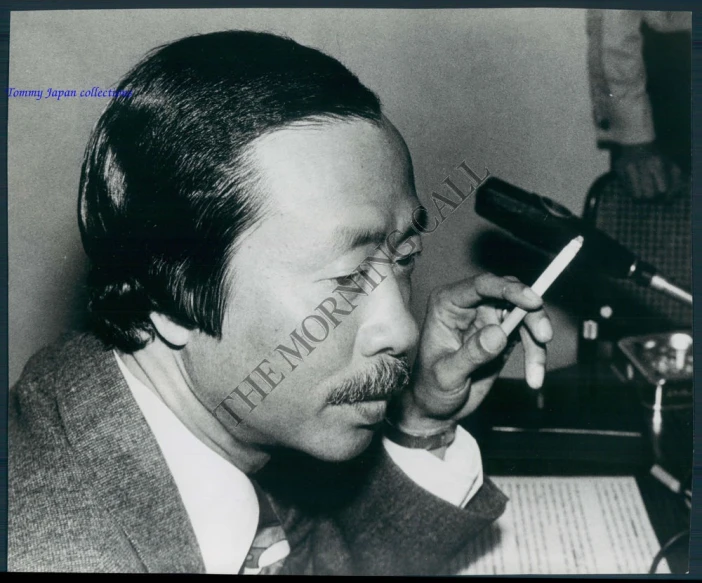 a man sitting at a desk with a cigarette