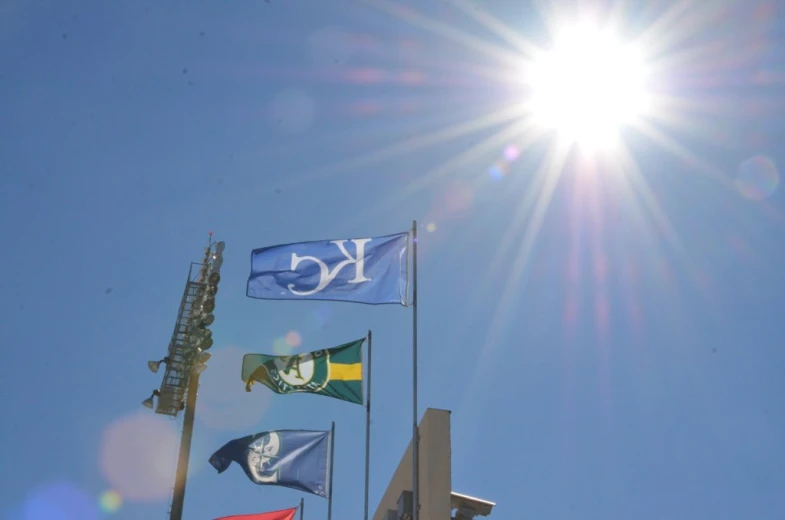 several flags flying in the sun behind a tall tower