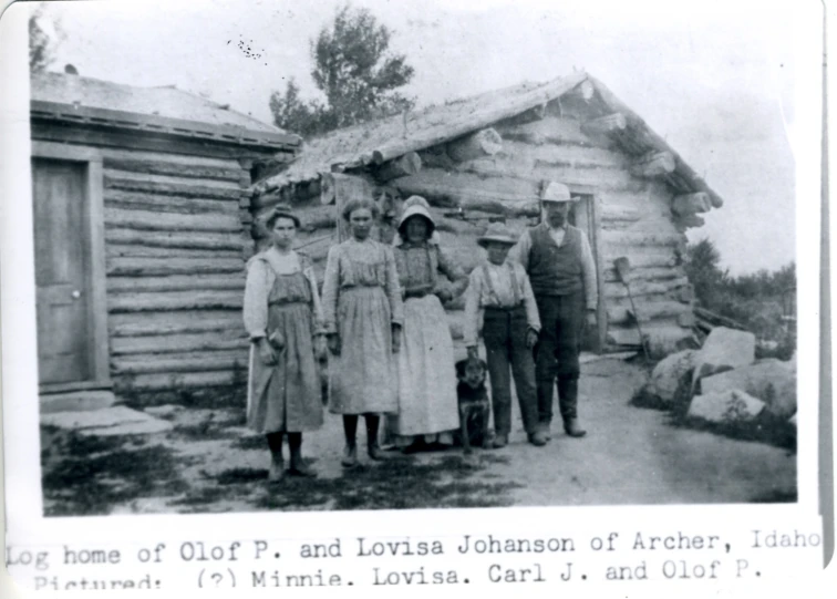 an old po of a family standing outside of a log cabin