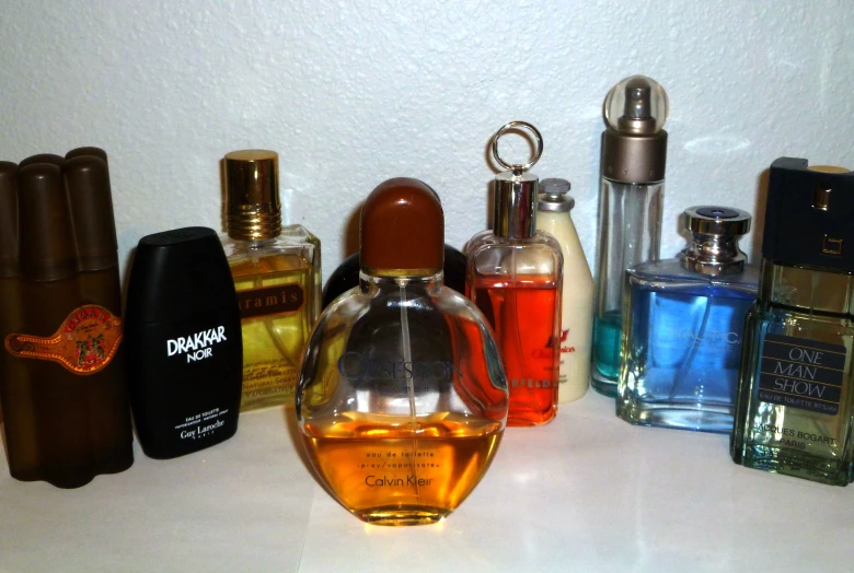 a collection of different perfumes lined up in front of a wall