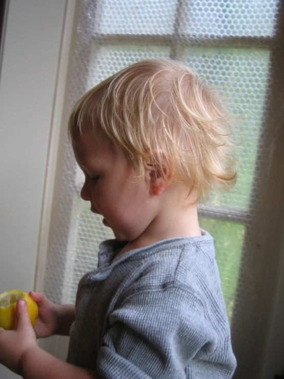 a toddler eating an apple by the window