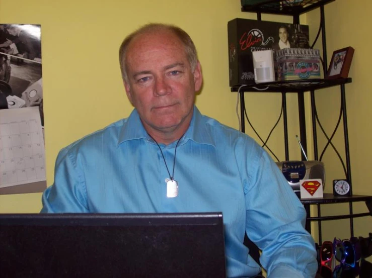 a man wearing a light blue shirt is sitting in front of a laptop computer