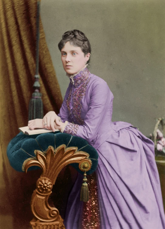 a woman in victorian dress sitting down reading a book