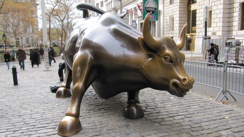 a bronze bull statue on a sidewalk in front of a building