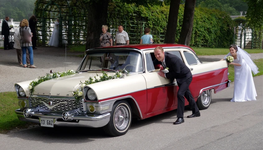 a couple getting into their old red and white car